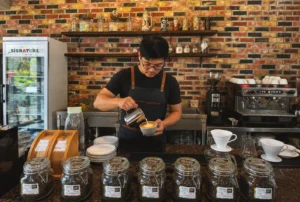A barista pouring latte art into a cup at the espresso bar of Wondellea Cafe & Resort, a premium specialty cafe in Cavite - Best Places for Coffee