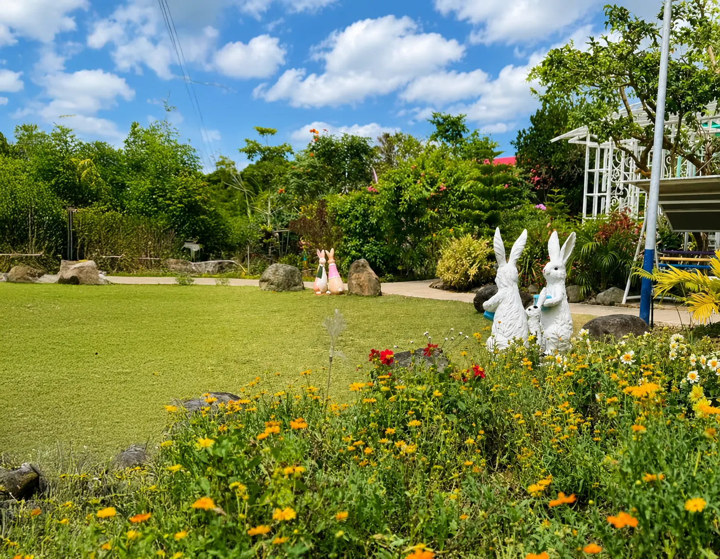 Beautiful garden with colorful flowers, decorative rabbit sculptures, and a spacious green lawn at Wondellea Cafe & Resort, Silang Cavite.