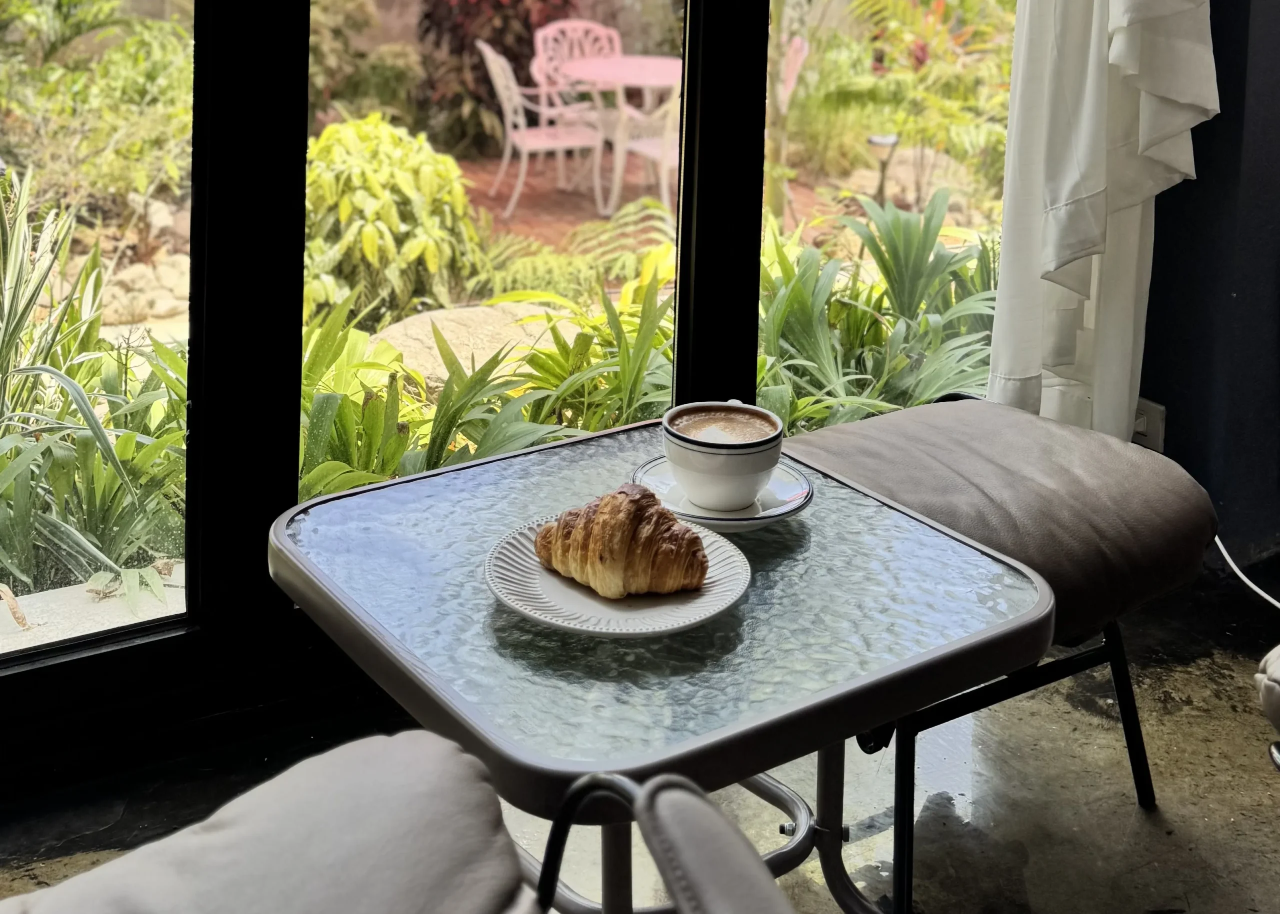 Croissant and hot coffee at a coffee shop near me open with a relaxing garden view