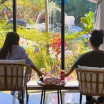 Guests relaxing by a garden view at a coffee shop near me open with comfortable seating