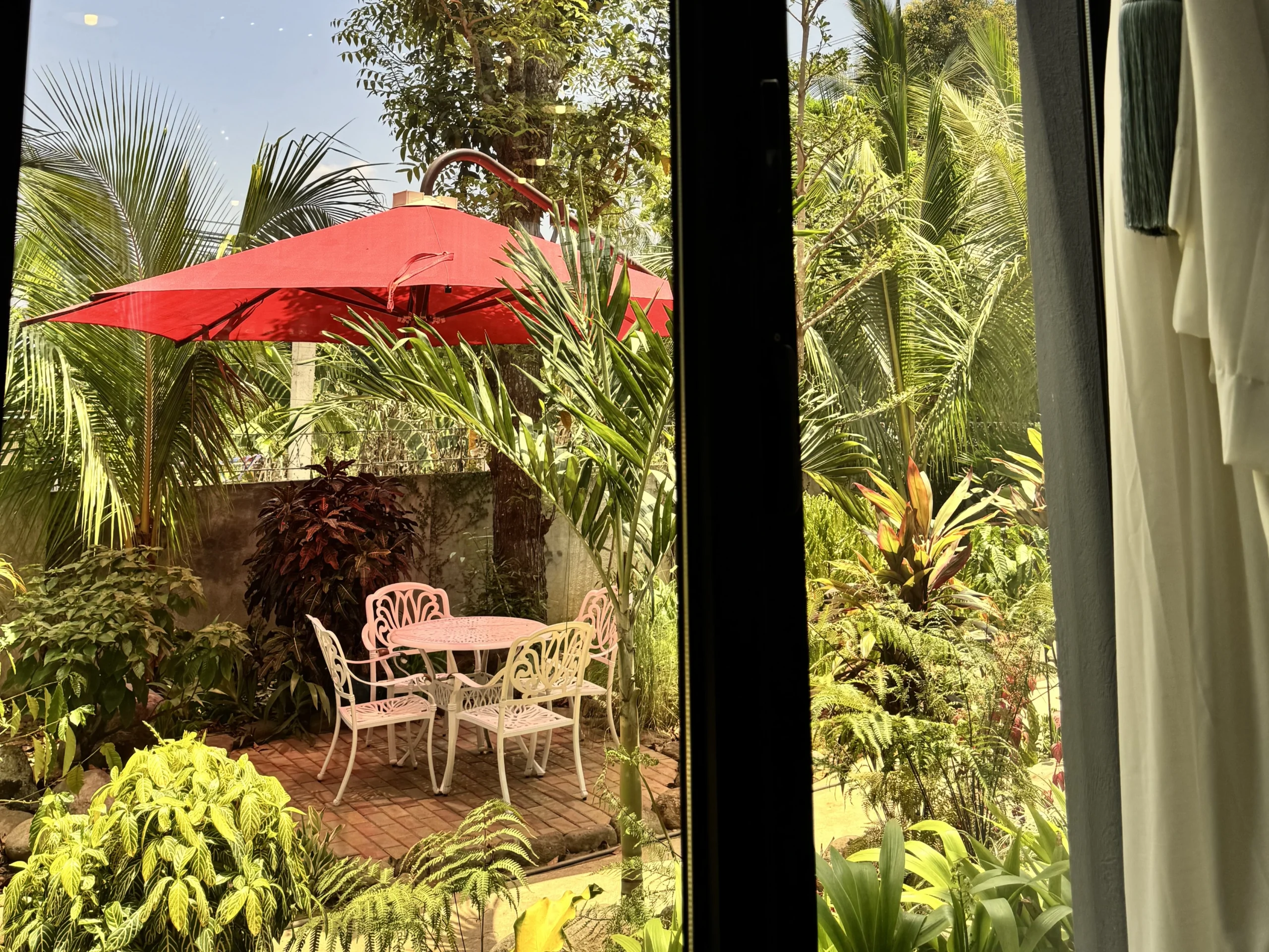 Shaded garden seating at an outdoor cafe in Cavite with a red umbrella