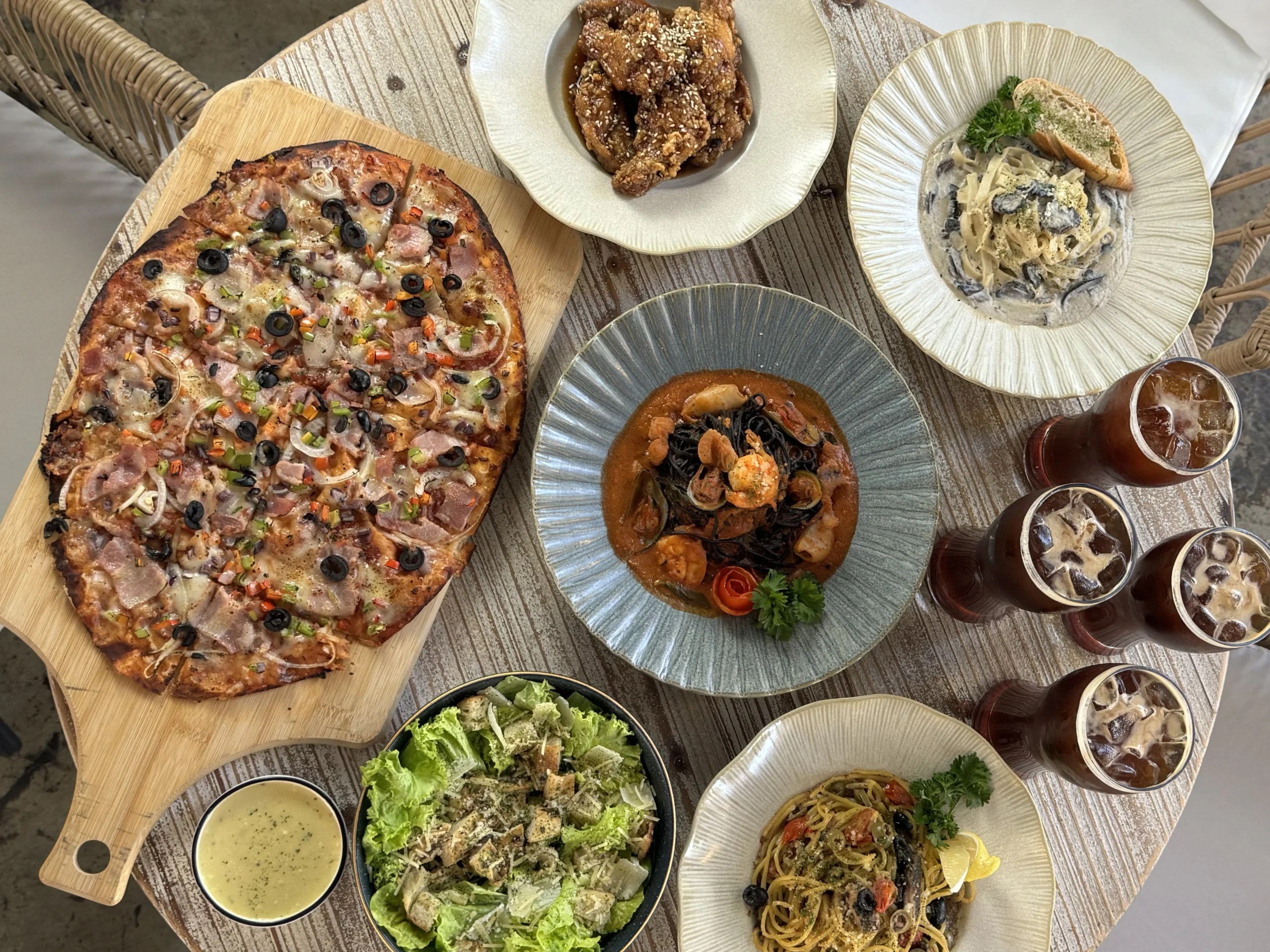Pizza, pasta, salad, and drinks served at an outdoor cafe in Cavite
